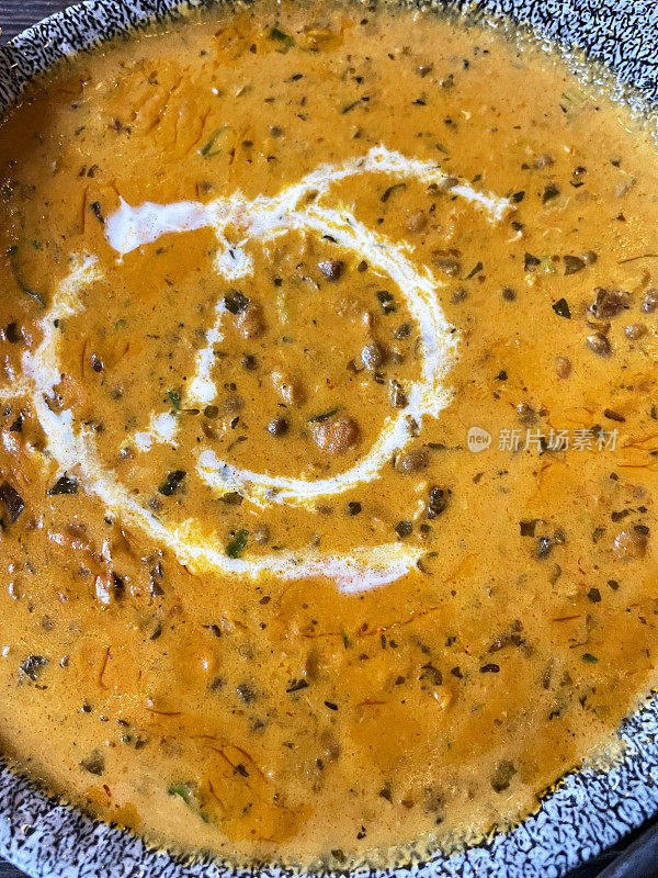 上菜的特写图片，里面装满了Dal makhani(黑扁豆和红芸豆)咖喱，淋着酸奶